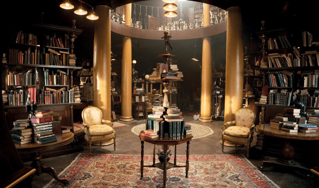 The foyer of A Z Fell's bookshop from the TV show Good Omens. It is cluttered with books and it all looks very antique.